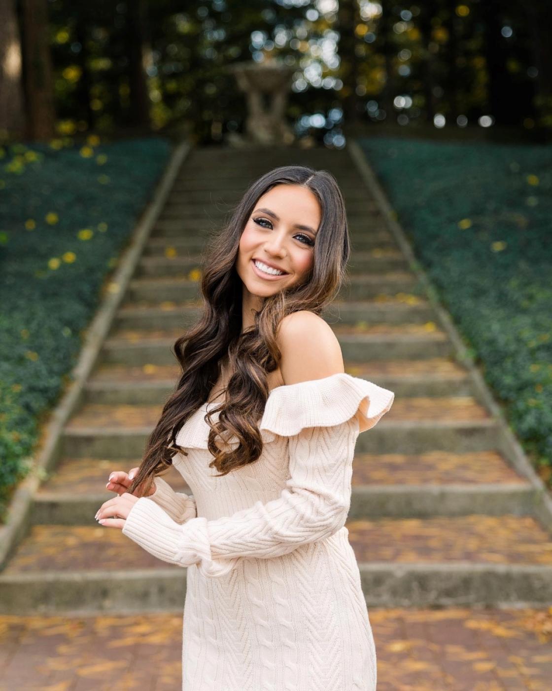 Portrait photo of a smiling person in the Cranbrook House Courtyard in the fall.