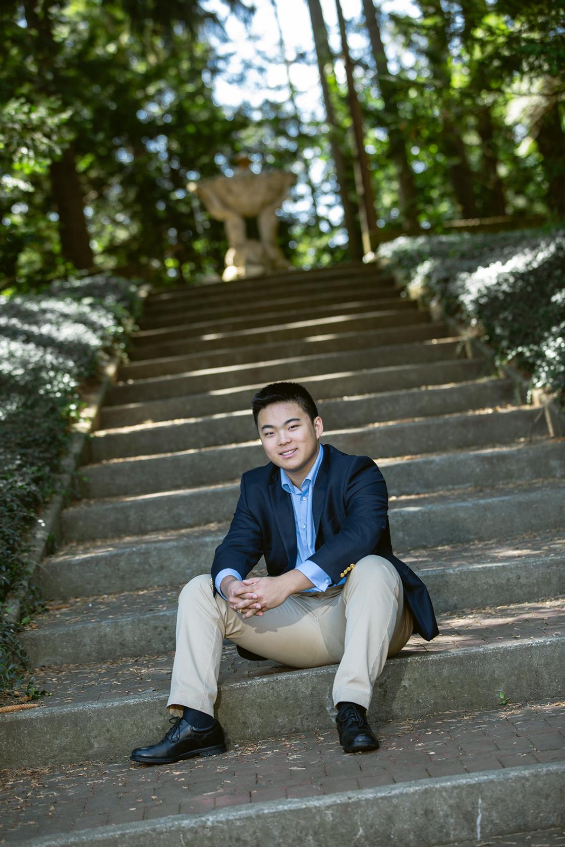 Photograph of someone in a suit sitting on the steps to The Mountain.