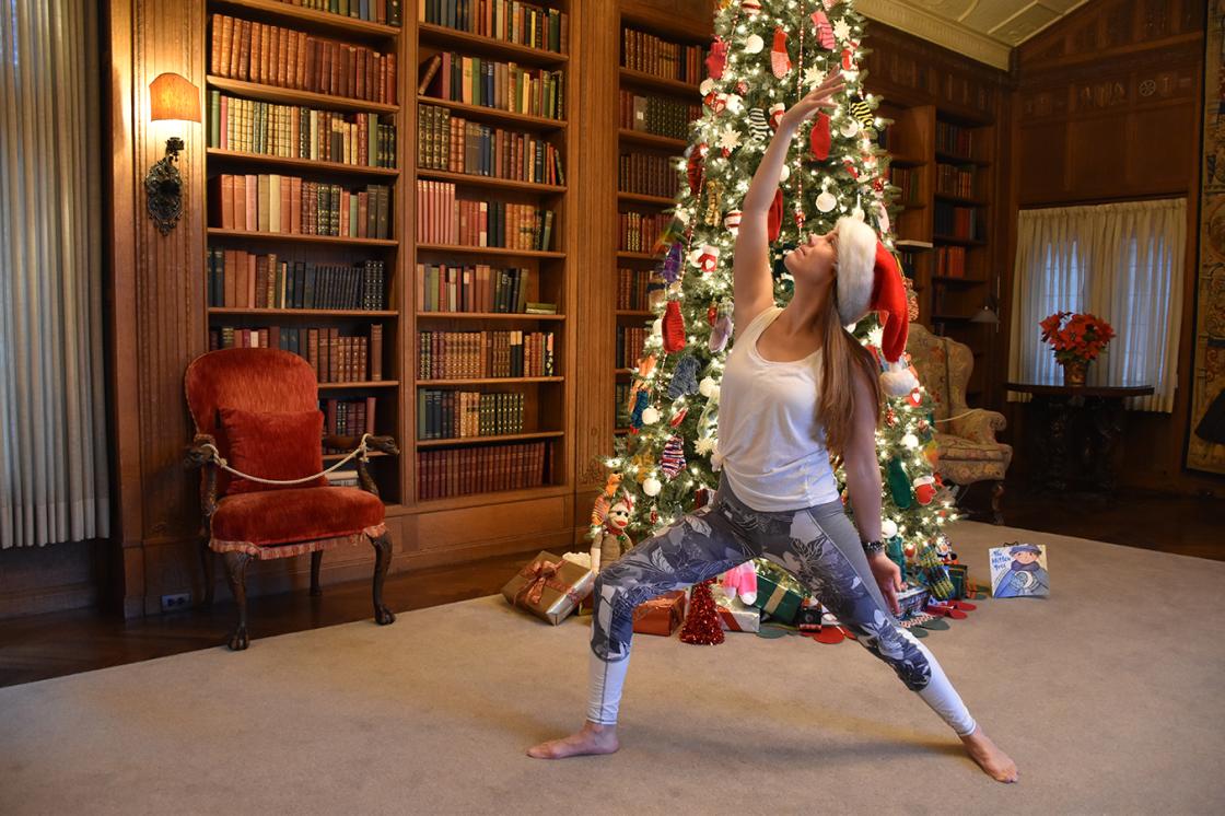 Photograph of a woman practicing yoga in the Cranbrook House Library during Holiday Splendor 2018.